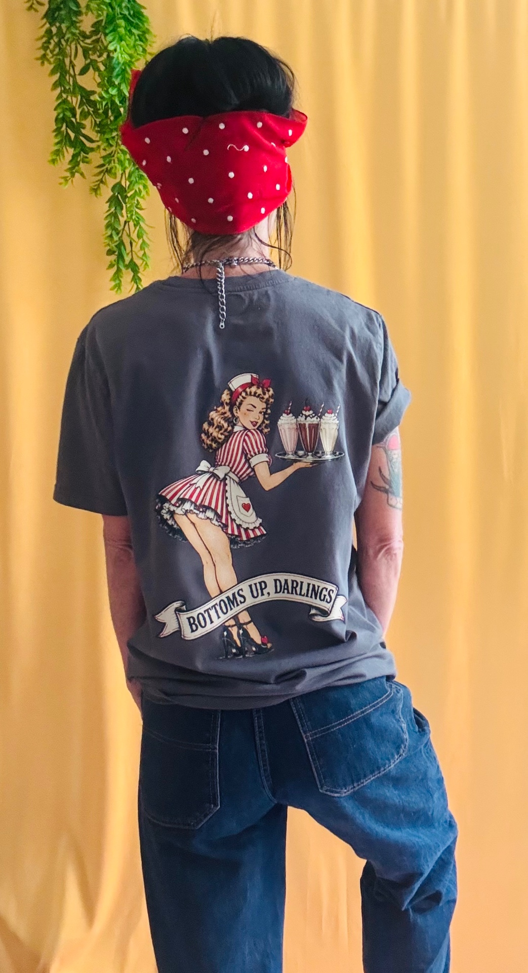 Bottoms Up Darlings tee back with large diner pin-up artwork on yellow backdrop